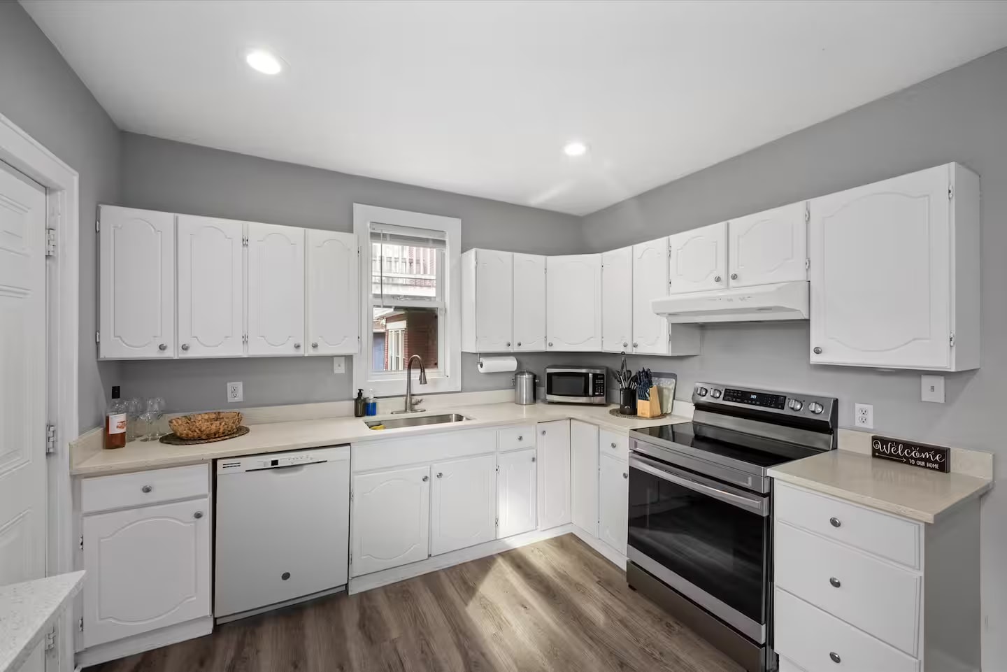 Bright full kitchen with white cabinetry and stainless-steel appliances